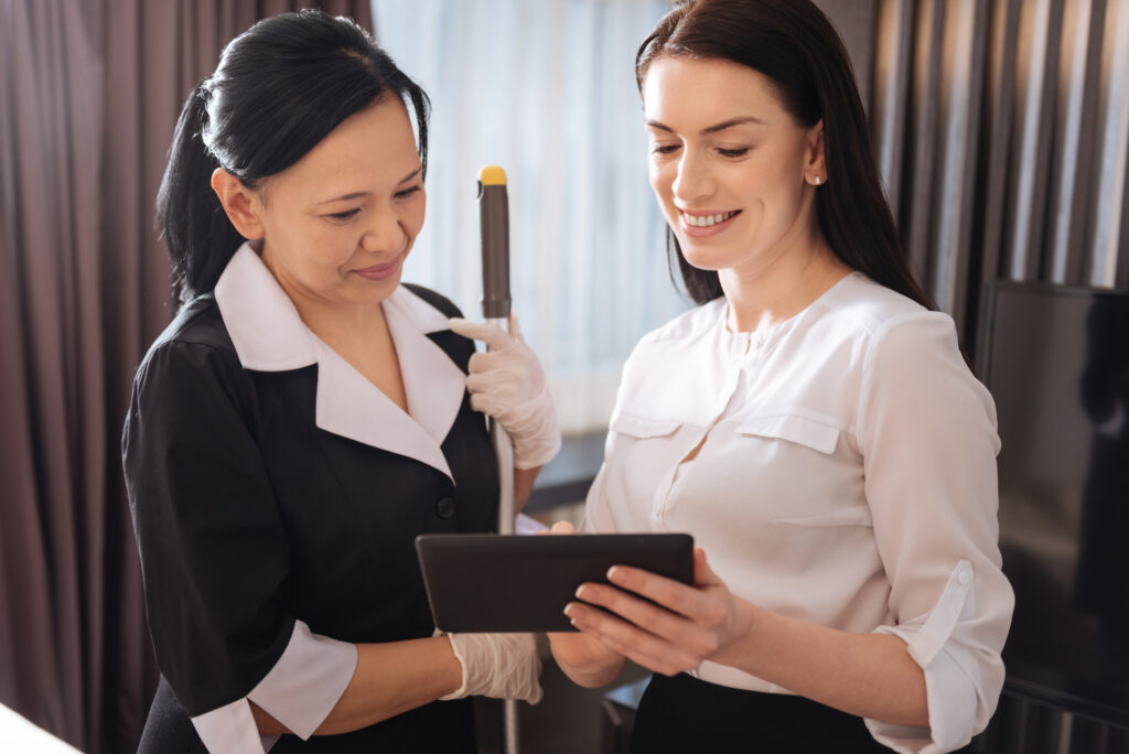 How Hotel Room Status Systems Improve Housekeeping Efficiency joyful pleasant women looking at the tablet screen